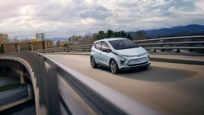 2023 Chevy Bolt EV driving on freeway overpass bridge during sunset hour