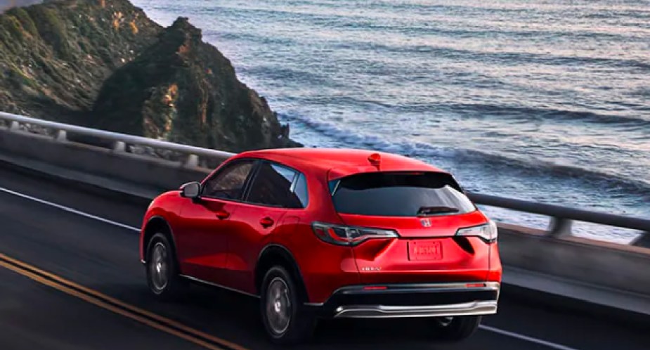 A red 2023 Honda HR-V subcompact SUV model is driving on the road. 
