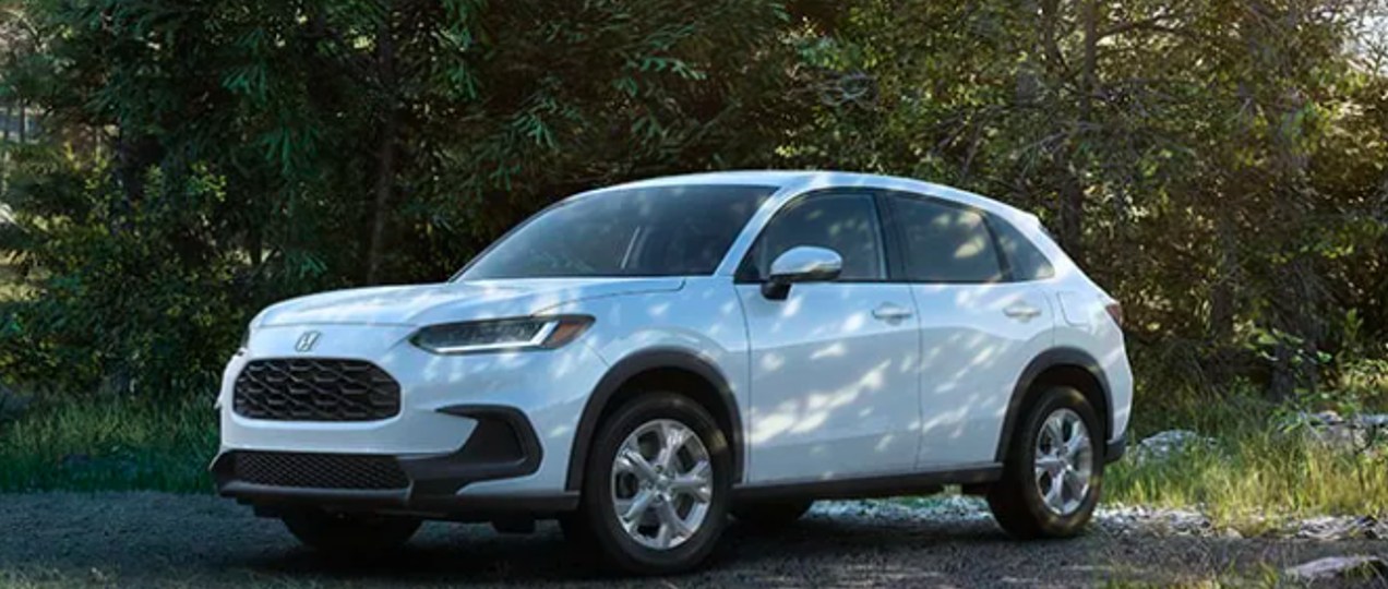 A white 2023 Honda HR-V subcompact SUV is parked outside in the shade.