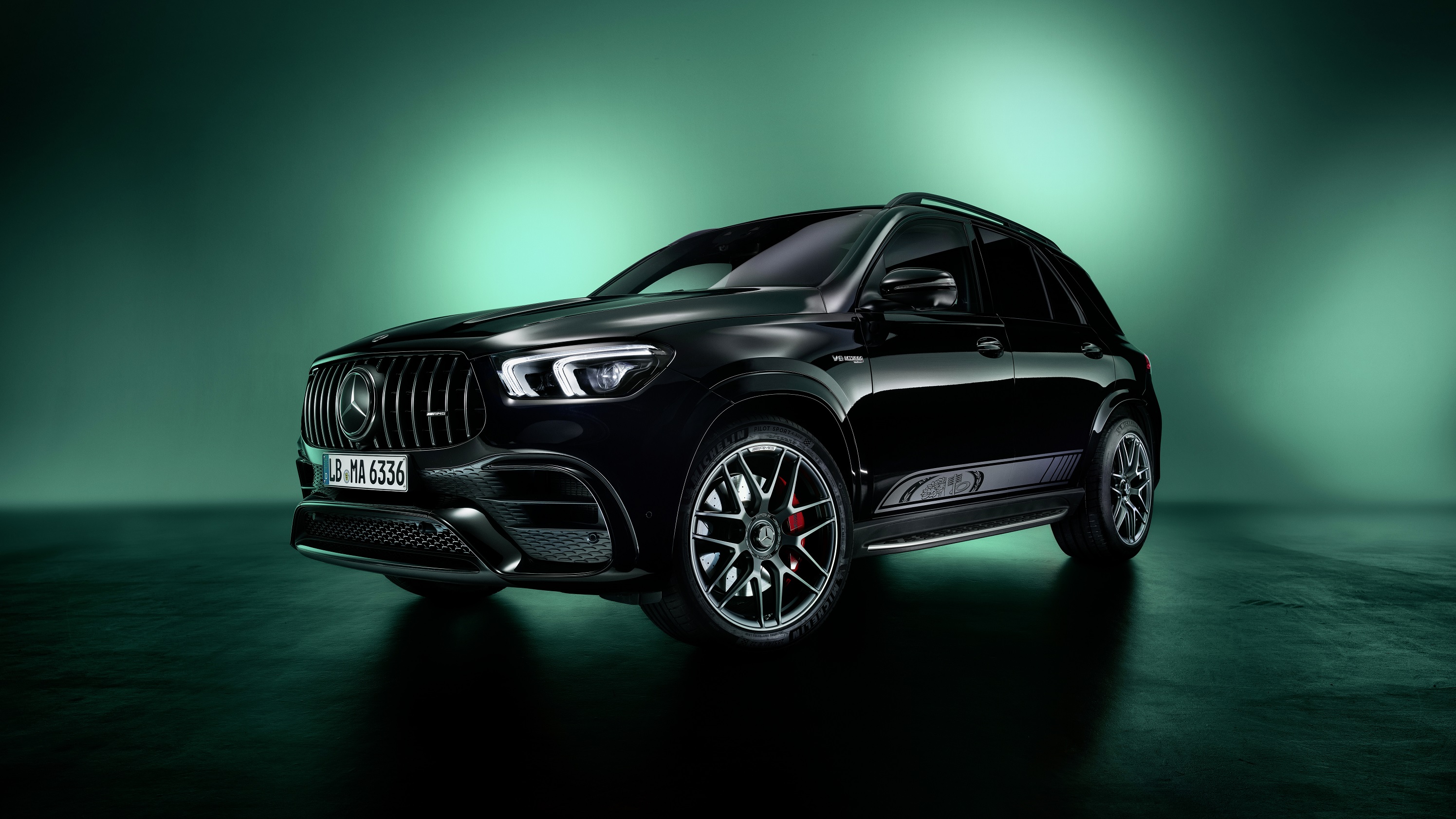 A black-and-silver 2023 Mercedes-AMG GLE 53 SUV Edition 55 in a green-lit studio