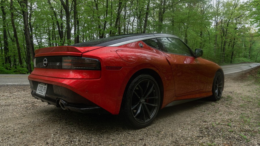 The rear 3/4 view of a red 2023 Nissan Z Performance on a forest road
