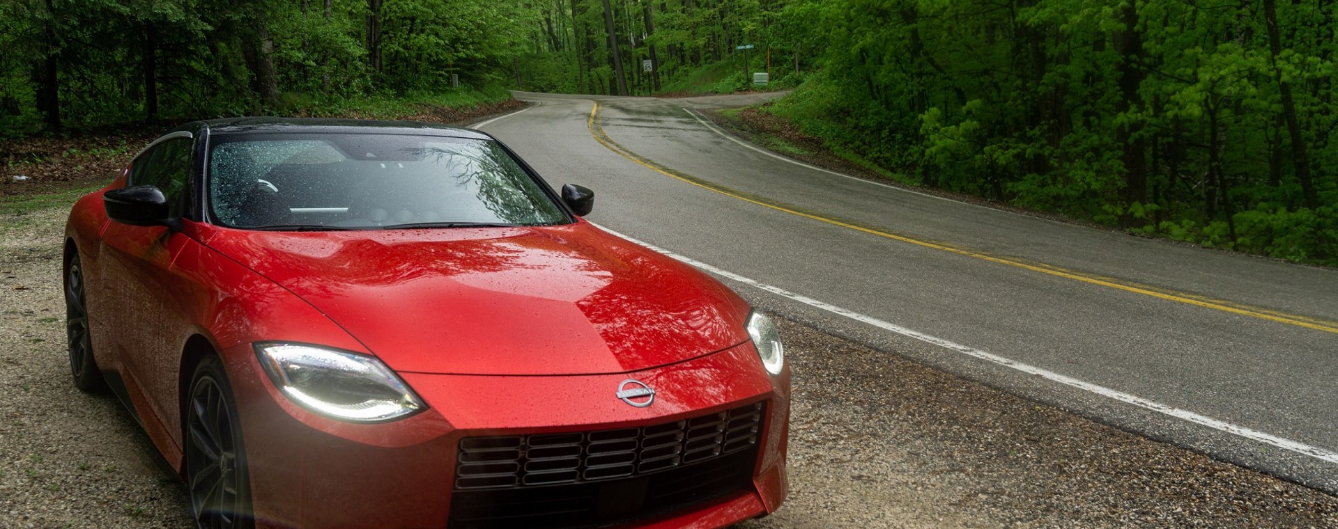 A red 2023 Nissan Z Performance by the side of a rainy forest road