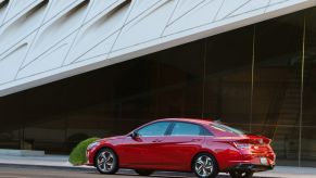 Red 2023 Hyundai Elantra midsize sedan parked in front a modern-looking building