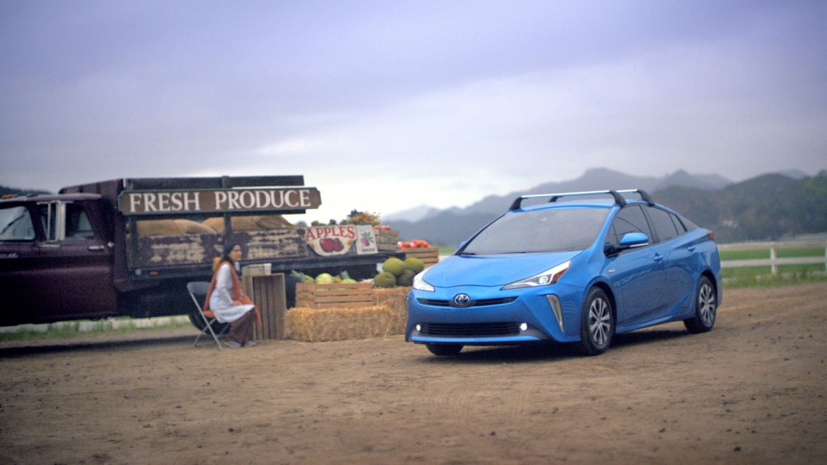 Blue Toyota Prius with crossbars parked near a produce stand. The 2023 Toyota Prius will likely receive a full redesign.
