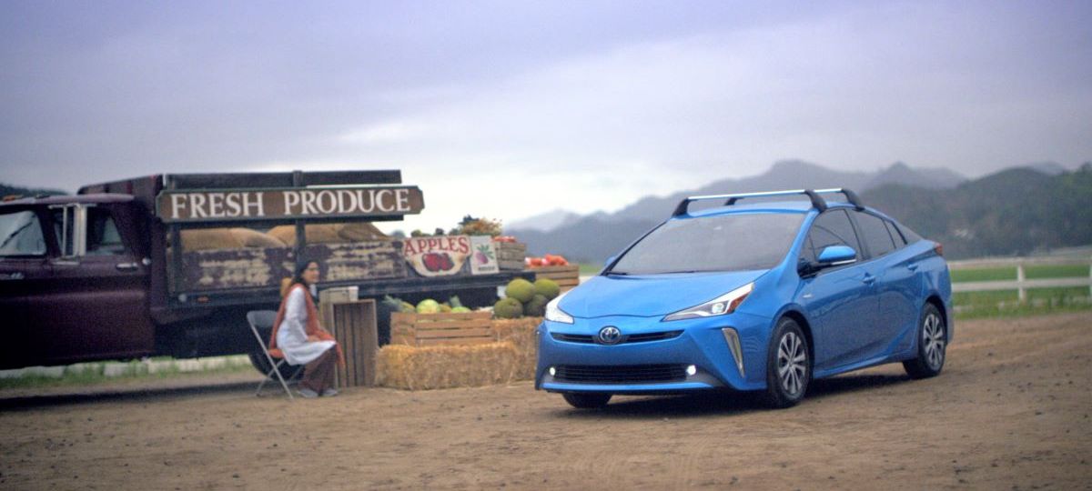 Blue Toyota Prius with crossbars parked near a produce stand. The 2023 Toyota Prius will likely receive a full redesign.