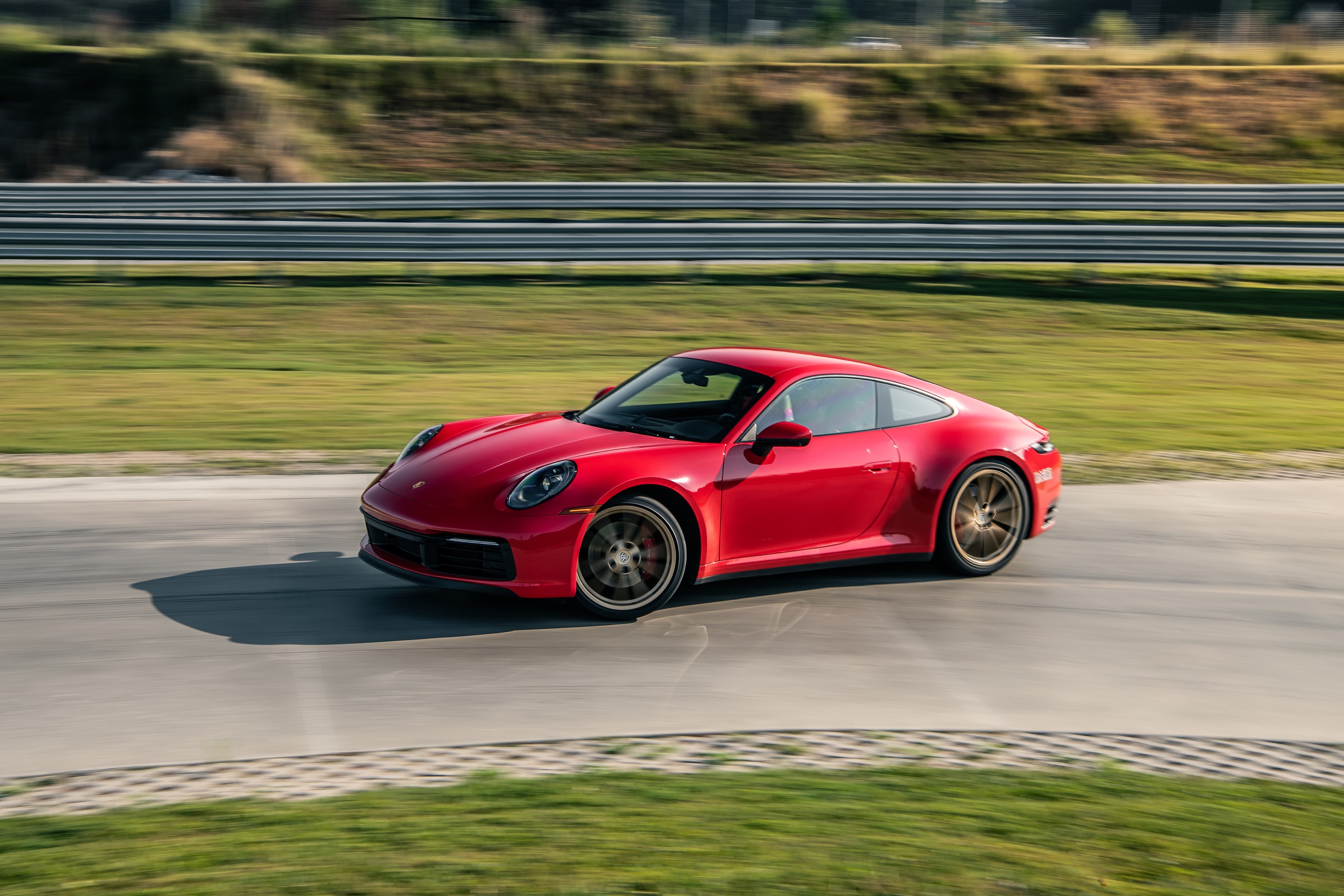 A red 2022 Porsche 911 Carrera S drives on a race track
