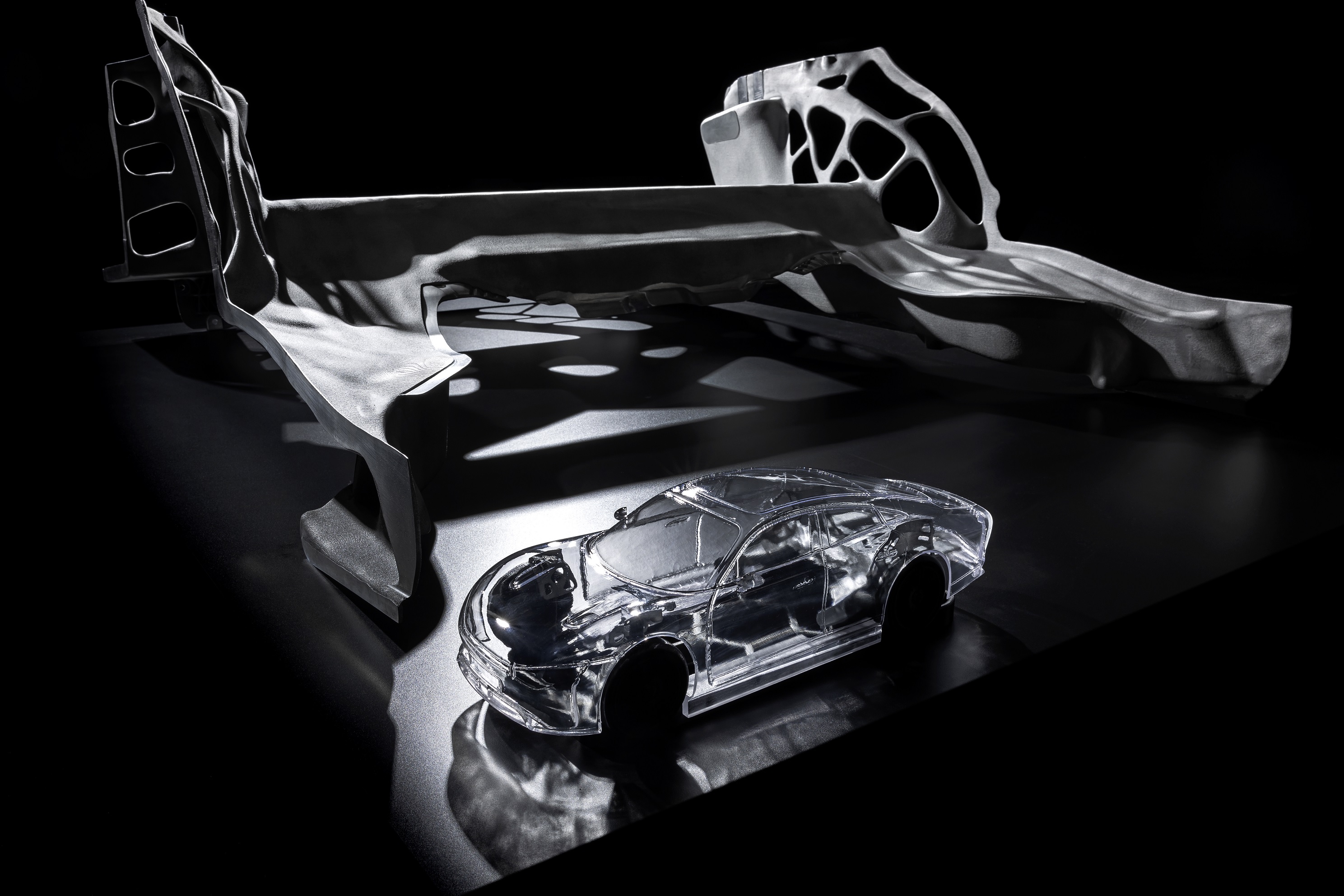 One of the Mercedes-Benz Vision EQXX Concept's cast-aluminum chassis pieces in front of a scale model