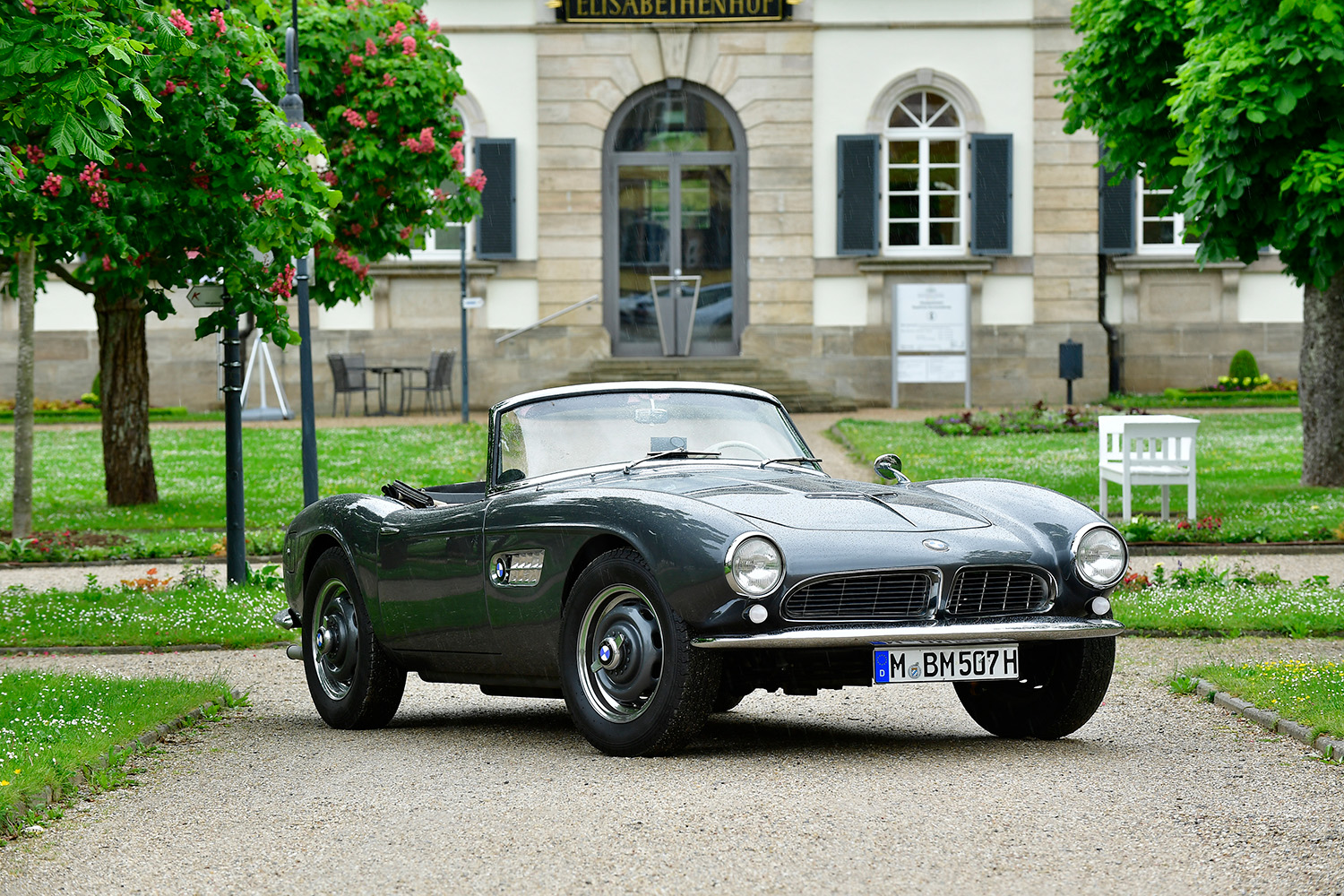 BMW 507 roadster parked in front of large house with gorgeous green grass and trees