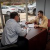 A person sitting doing a car deal, potentially car leasing.