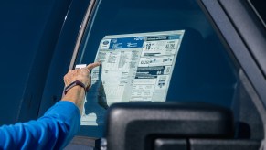 A customer inspects the Monroney sticker on a Ford vehicle at the Helfman Ford dealership