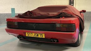 Ferrari Testarossa in red sitting abandoned under a car cover