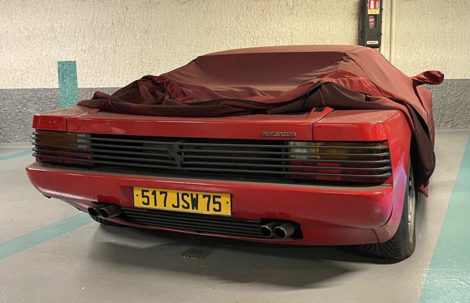 Ferrari Testarossa in red sitting abandoned under a car cover