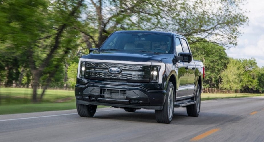 A black 2022 Ford F-150 Lightning Platinum is driving on the road.