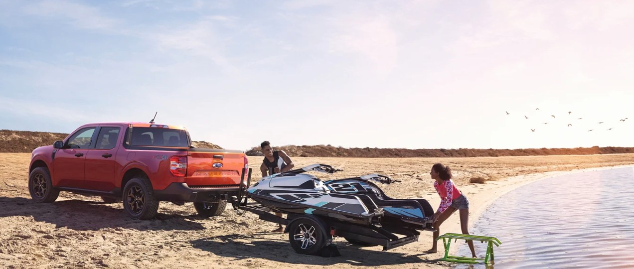 A red 2022 Ford Maverick is towing jetskis.