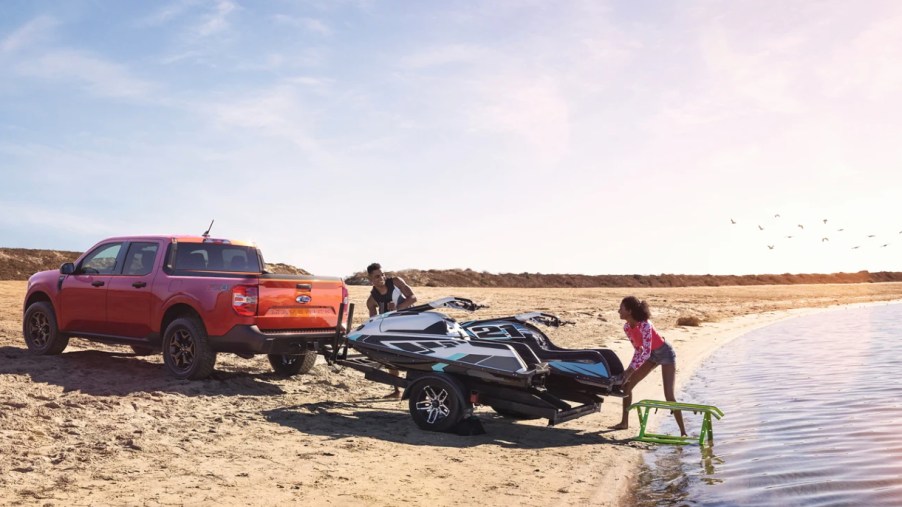 A red 2022 Ford Maverick is towing jetskis.