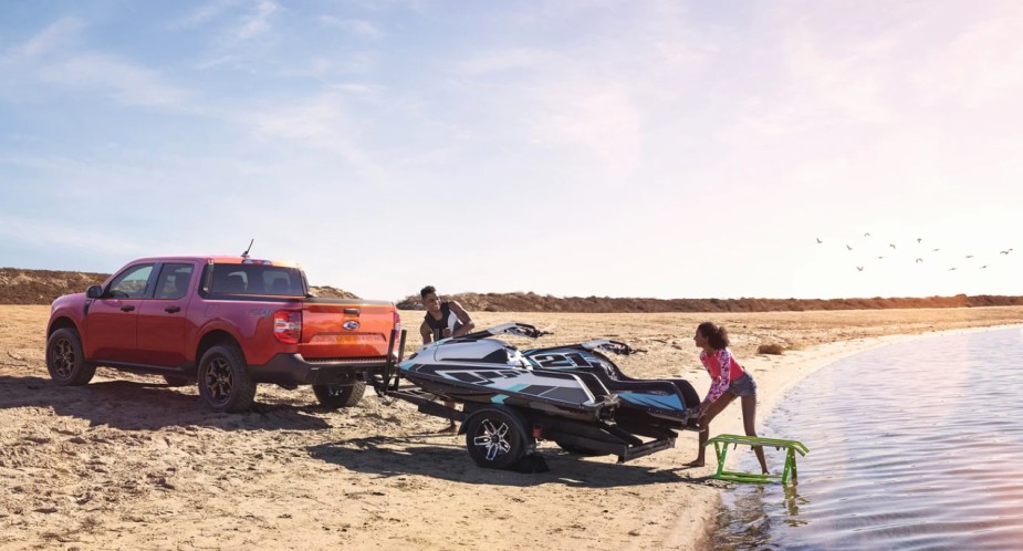 A red 2022 Ford Maverick is towing jetskis.