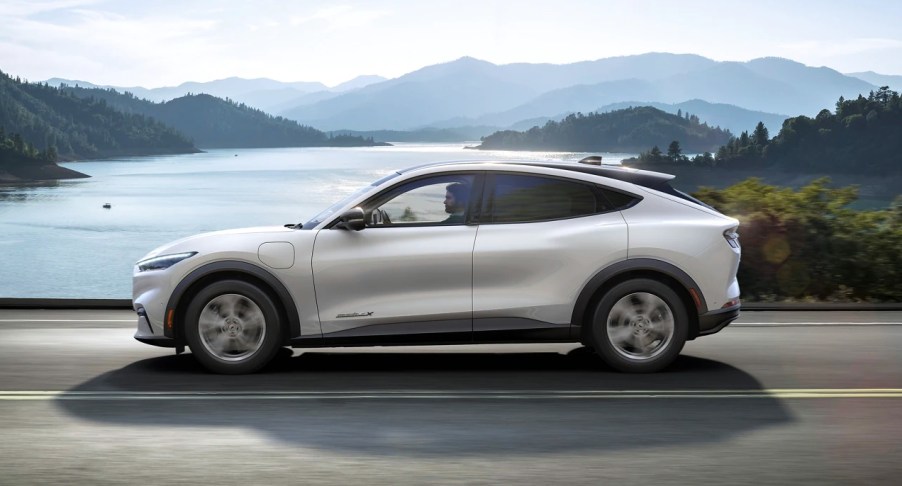 A white 2022 Ford Mustang Mach-E electric SUV is driving on the road.