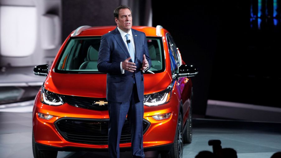 GM president Mark Reus standing in front of an orange Chevy Bolt.