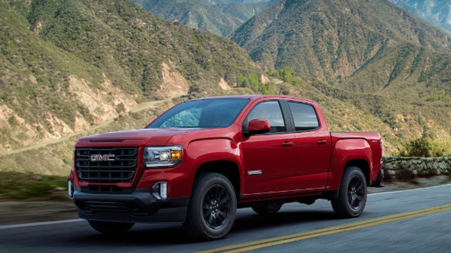 A red 2022 GMC Canyon is driving on the road.