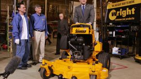 George W. Bush riding a stand-on lawn mower during a tour of Wright Manufacturing in Fredrick, Maryland