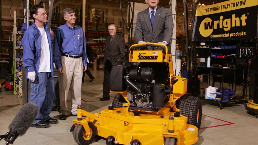 George W. Bush riding a stand-on lawn mower during a tour of Wright Manufacturing in Fredrick, Maryland