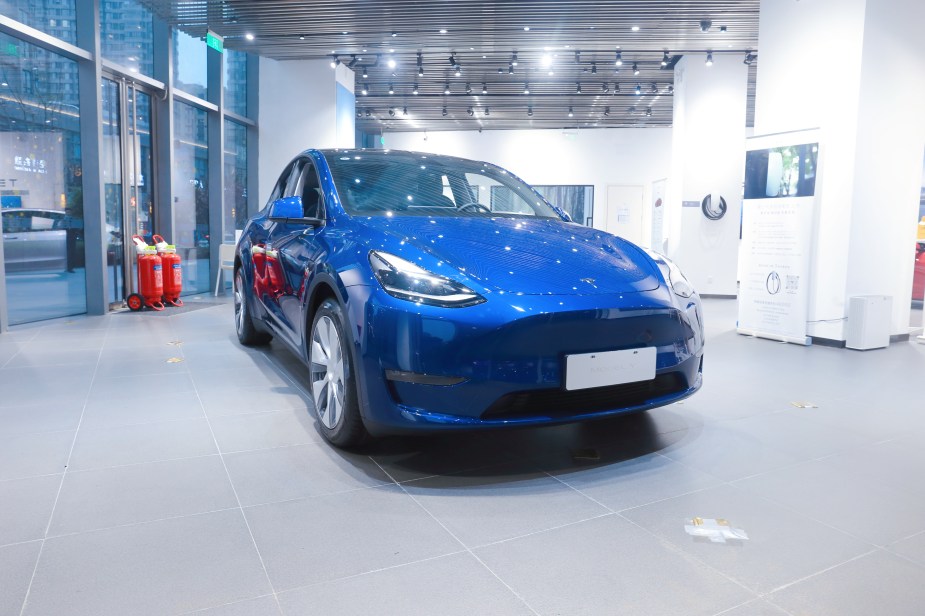 A blue Tesla Model 3 parked in a showroom.