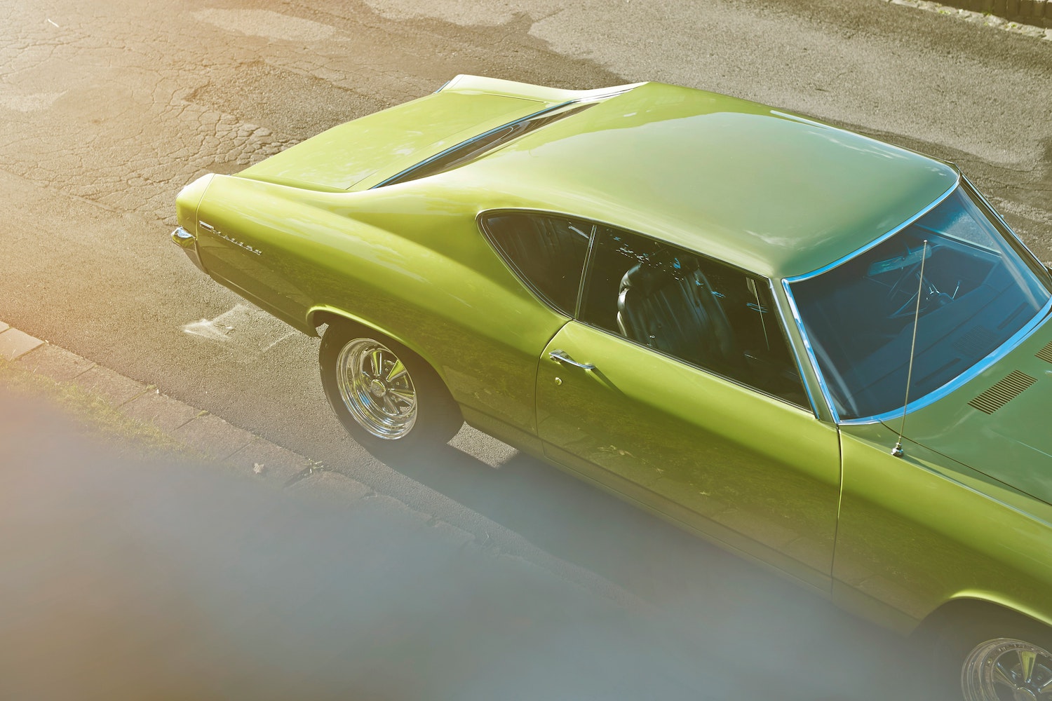 Overhead view of an olive green colored muscle car parked on the street.