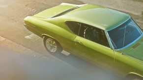 Overhead view of an olive green colored muscle car parked on the street.