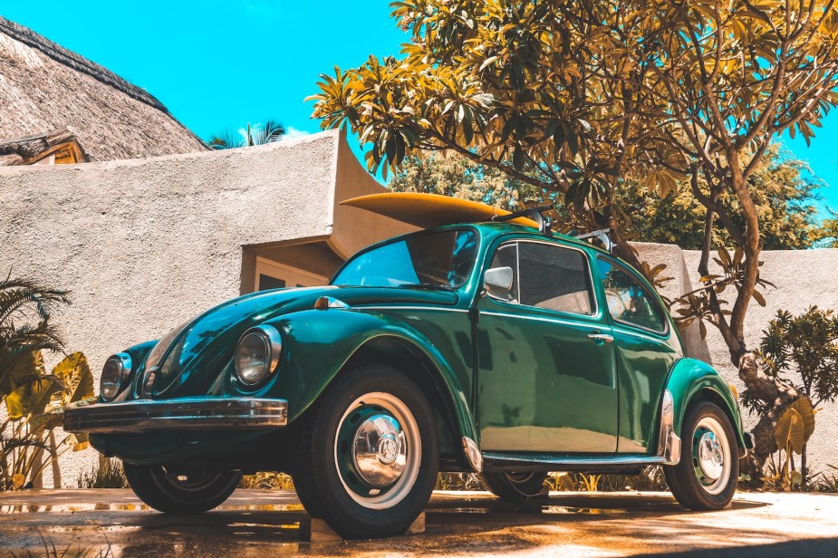 Closeup of a dark green VW bug parked in a driveway.