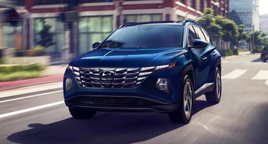 A blue 2022 Hyundai Tucson Hybrid SUV is driving on the road. 