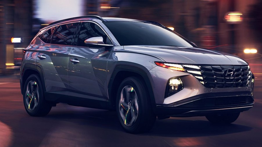 A gray 2022 Hyundai Tucson Plug-In Hybrid SUV is driving on the road.