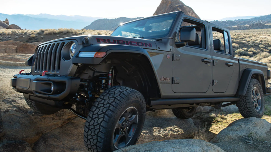 A 2022 Jeep Gladiator Rubicon midsize pickup truck climbing over rocks and boulders off-road