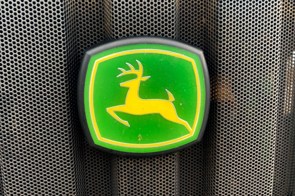 A green and yellow John Deere logo on a John Deere zero-turn lawn mower.