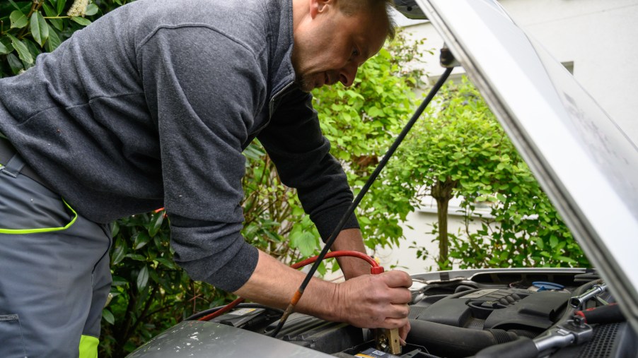 A person that hopefully will choose the best jump starter, jump starting their car.