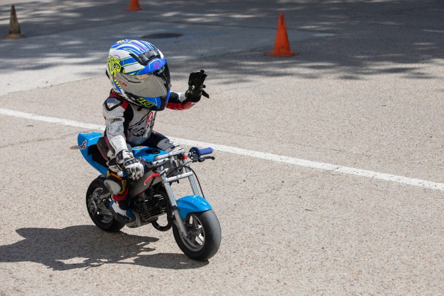 A kid riding a kids motorcycle outdoors.
