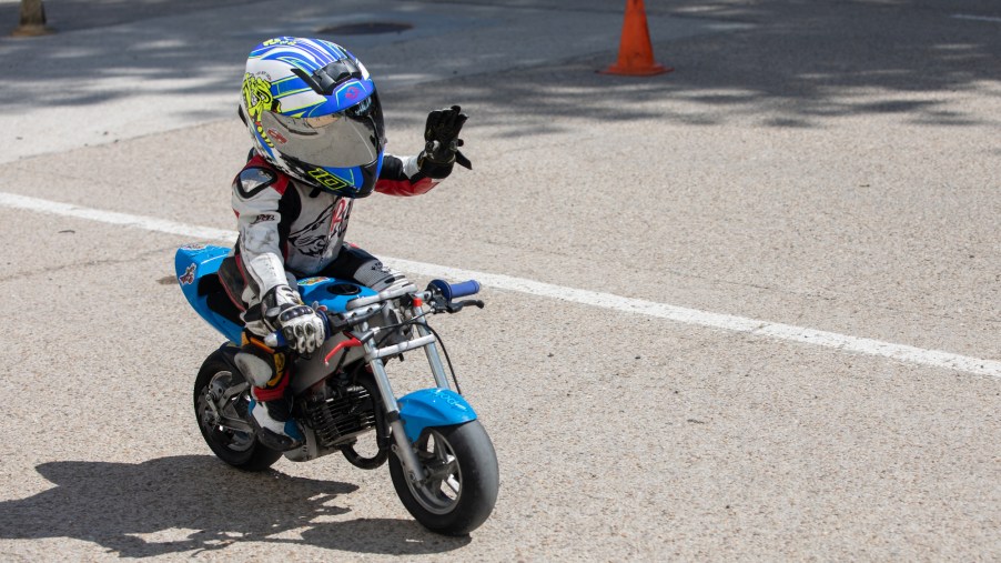 A kid riding a kids motorcycle outdoors.