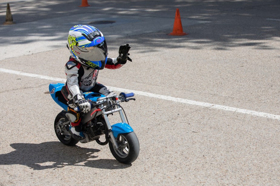 A kid riding a kids motorcycle outdoors. 
