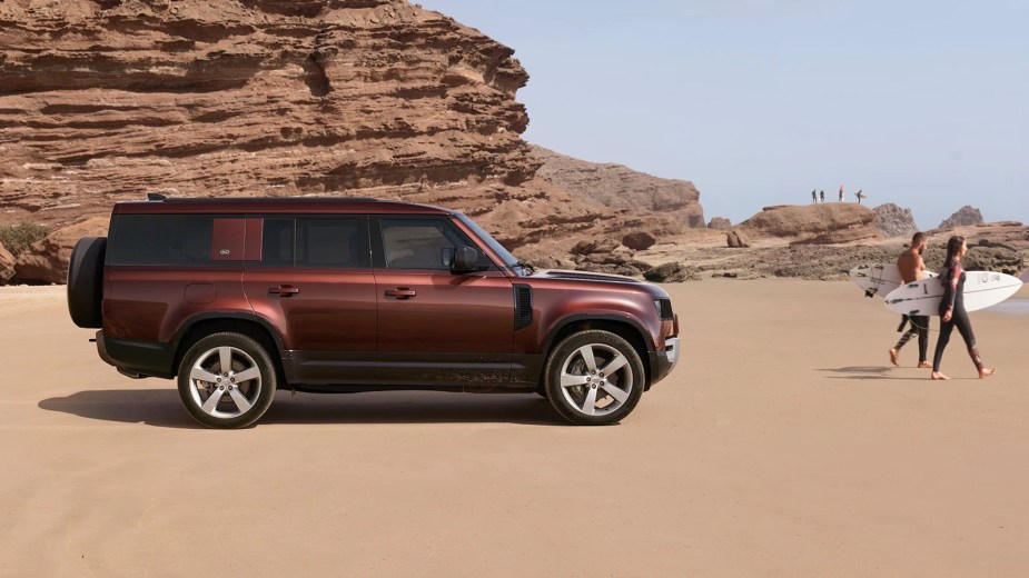 A maroon 2023 Land Rover Defender 130 at the beach.