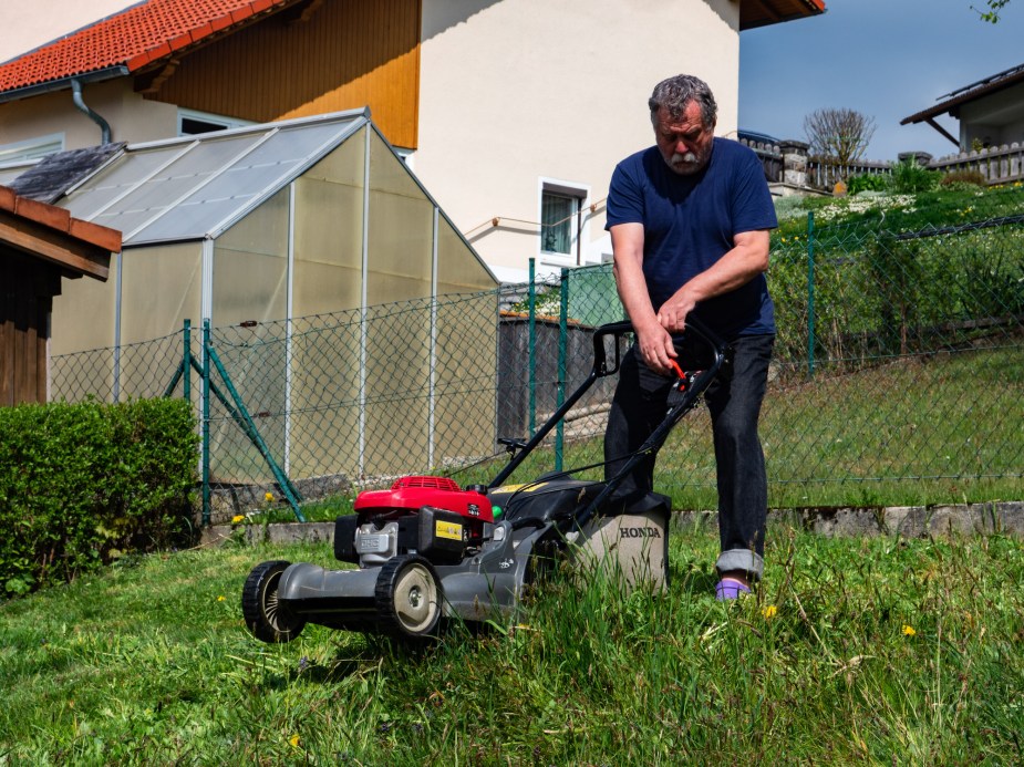 A person pushing a lawn mower, that could be across uneven ground. 