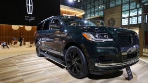 A 2022 Lincoln Navigator in balck parked indoors on wooden ceramic looking floors.