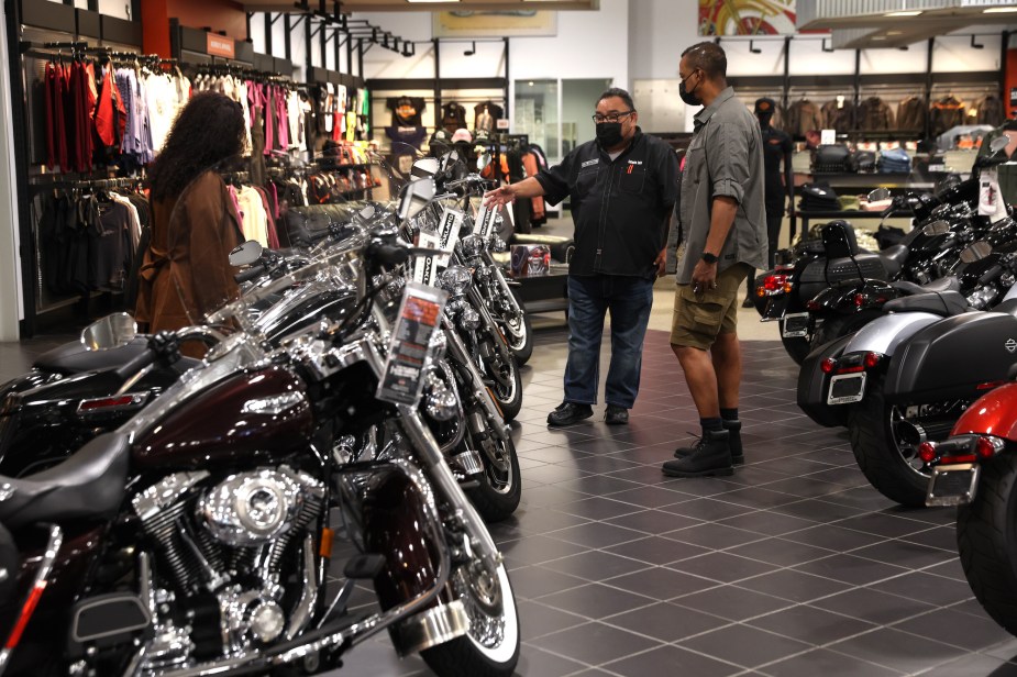 A person in motorcycle sales talking to potential customers in a bike shop. 