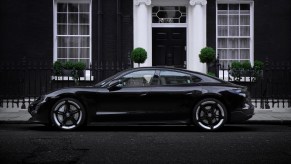 A black Porsche Taycan parked in front of a black building.