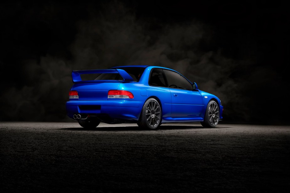 The rear 3/4 view of a blue Prodrive P25 in a black studio
