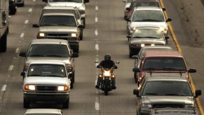 A motorcycle rider lane-spitting between cars during the commute