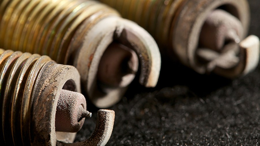 Closeup of sooty, sandy deposits on the electrodes of three spark plugs.