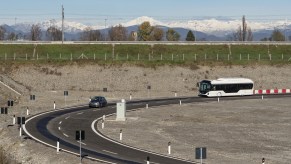 A gray Fiat 500 EV and white bus running on Stellantis' Italian test track testing a new wireless charging system