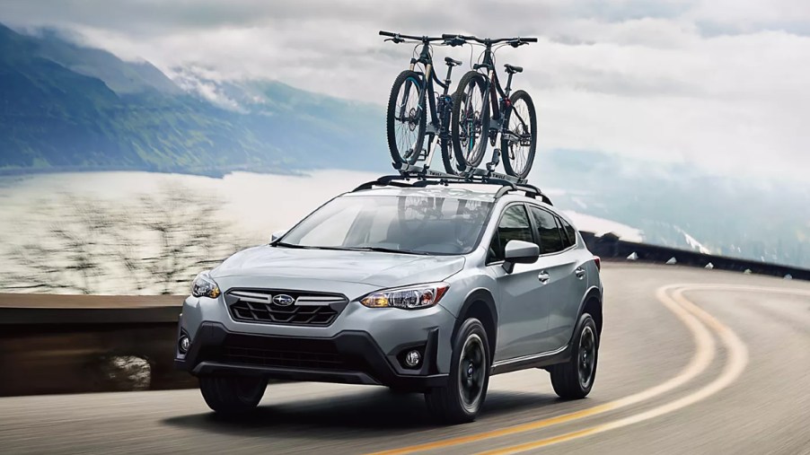 A blue 2022 Subaru Crosstrek small off-road SUV is driving on the road.