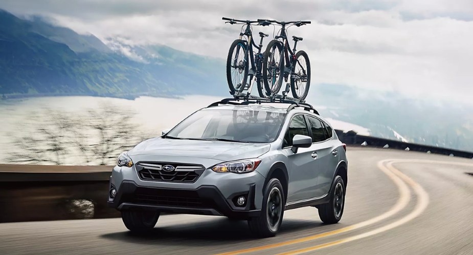 A blue 2022 Subaru Crosstrek small off-road SUV is driving on the road. 