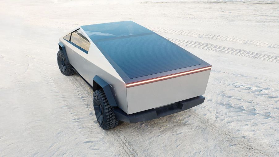 A rear shot of the Tesla Cybertruck's closed bed with the electric truck parked on a white sandy beach