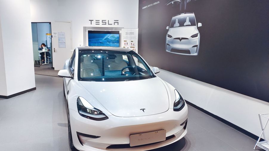 A white Tesla Model 3, which is an EVs With the Longest Range, parked indoors.